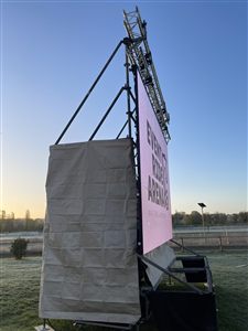 Écran LED monté sur structure au coucher du soleil, sur un terrain de sport
